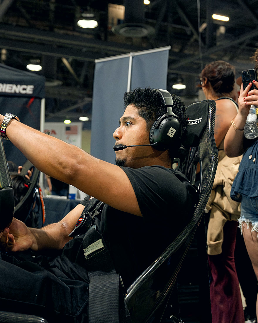 A driver mid-race at a Trackside activation while a spectator snaps photos