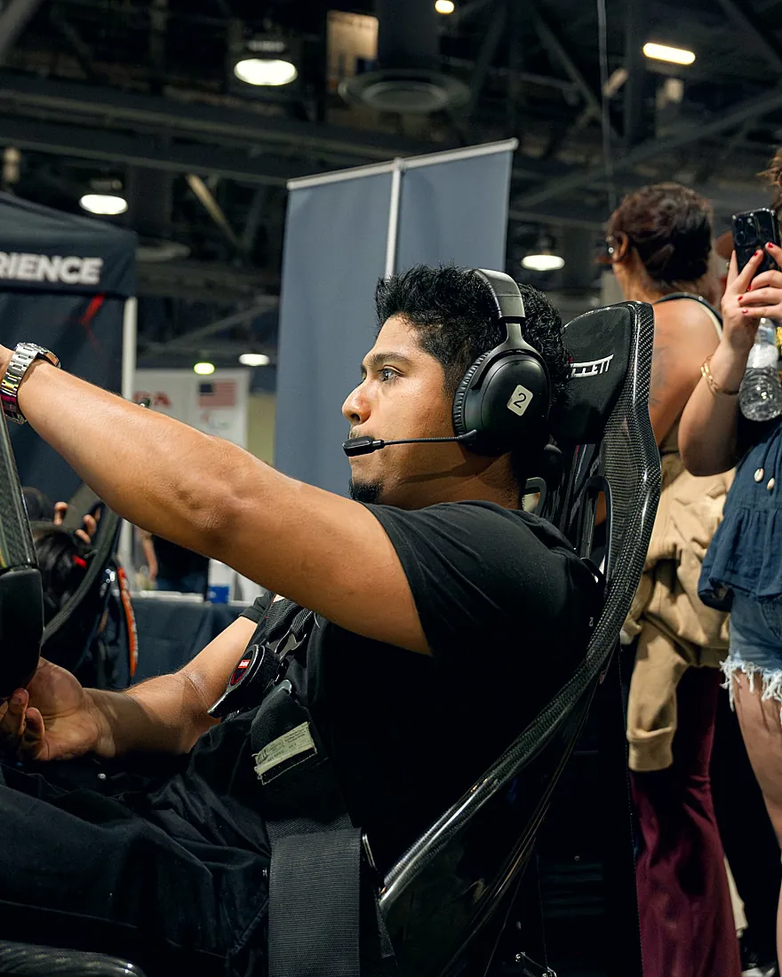 A driver mid-race at a Trackside activation while a spectator snaps photos