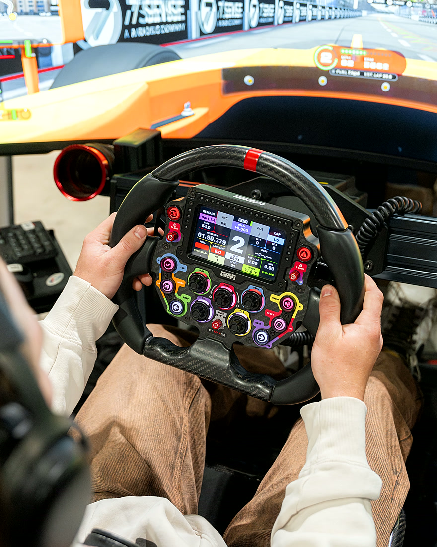 Close-up of a professional racing wheel with the race live on screen