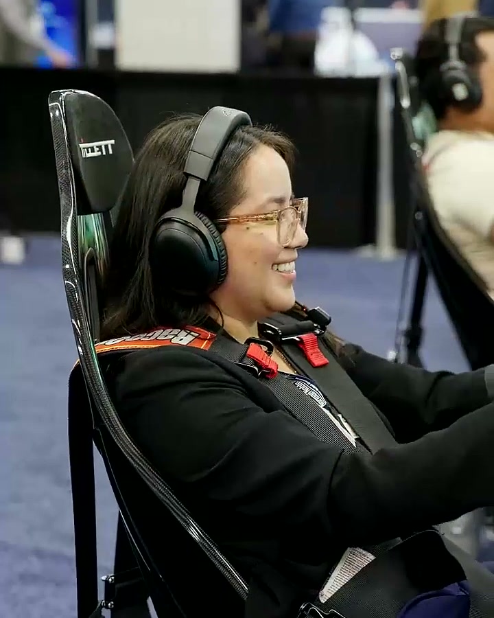 A smiling attendee racing in a full-motion simulator at MD&M West