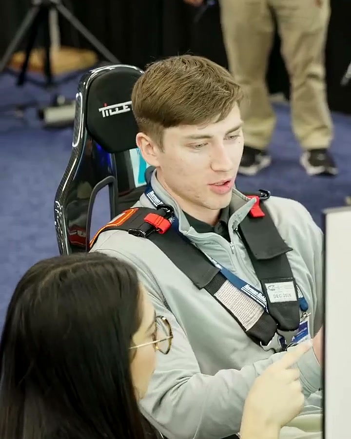 A harnessed driver talking with booth staff between sessions