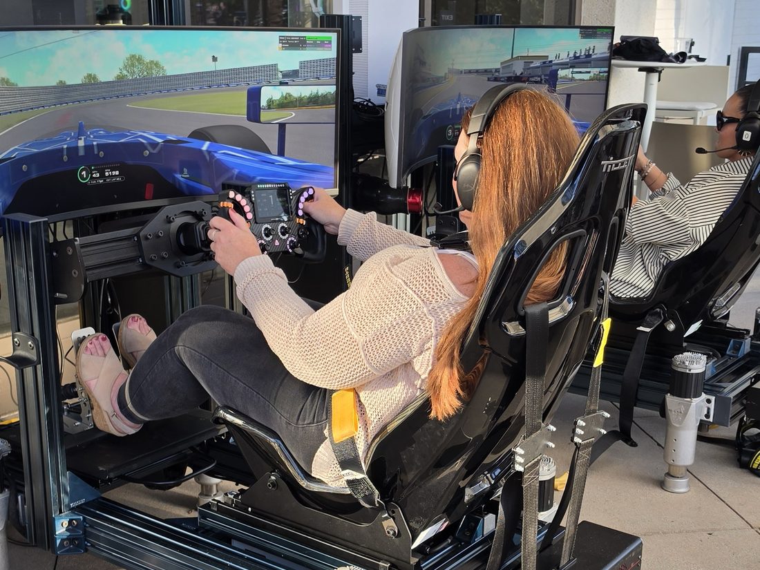 Two guests racing side by side on full-motion simulators during the Mercer Formula 4 time trial