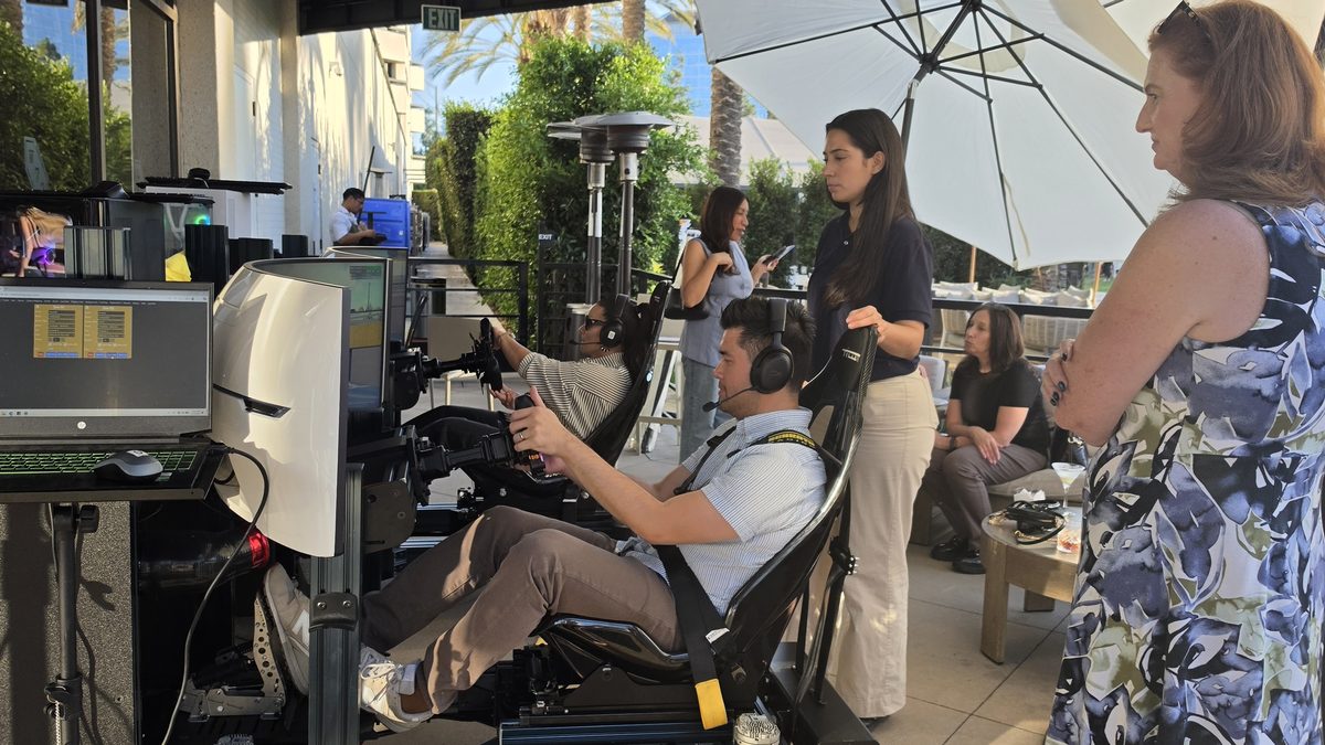Guests watching and waiting their turn at the Trackside simulators during the Mercer reception in Irvine