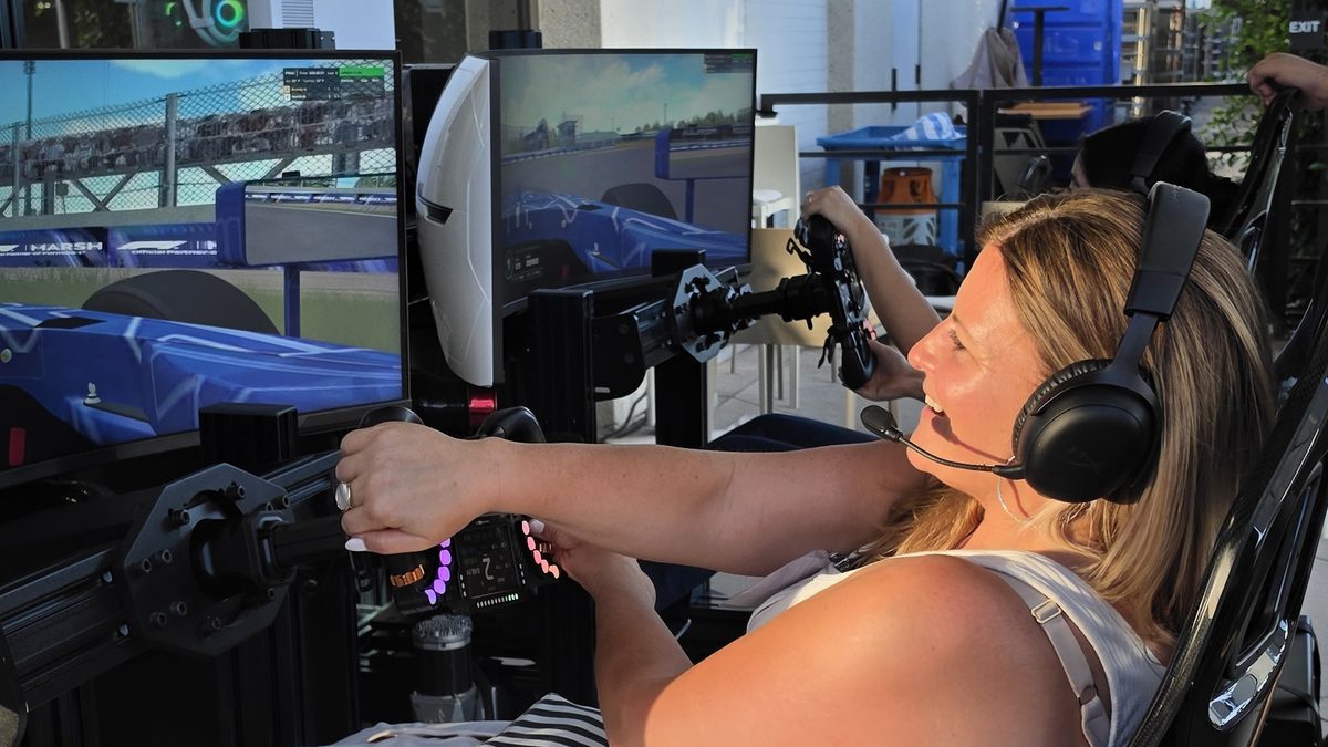A first-time driver mid-session on a full-motion racing simulator at the Mercer reception