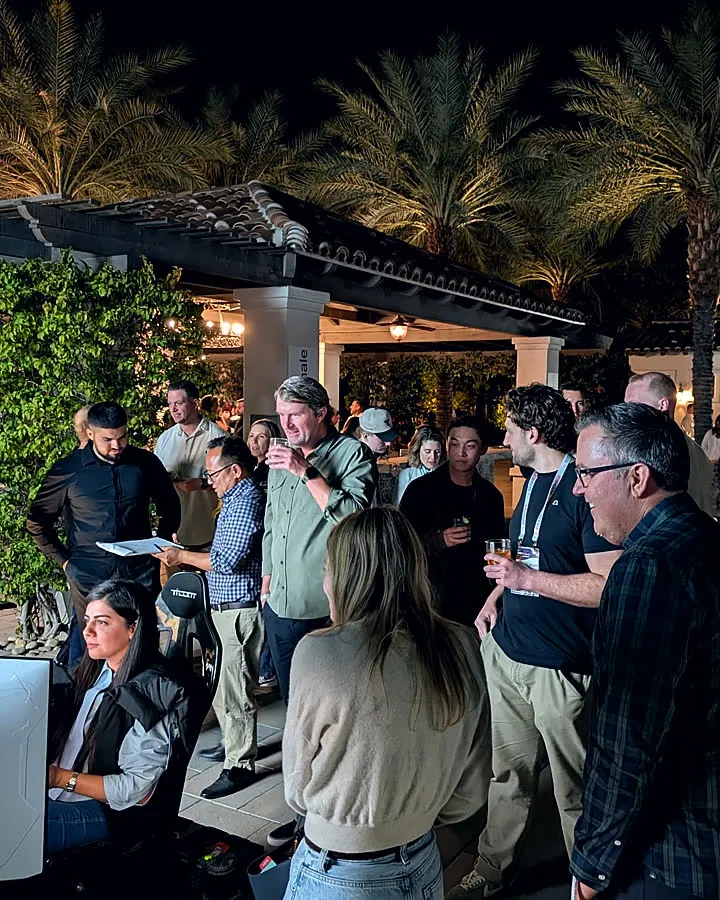 An upscale poolside evening event with guests gathered around a Trackside simulator